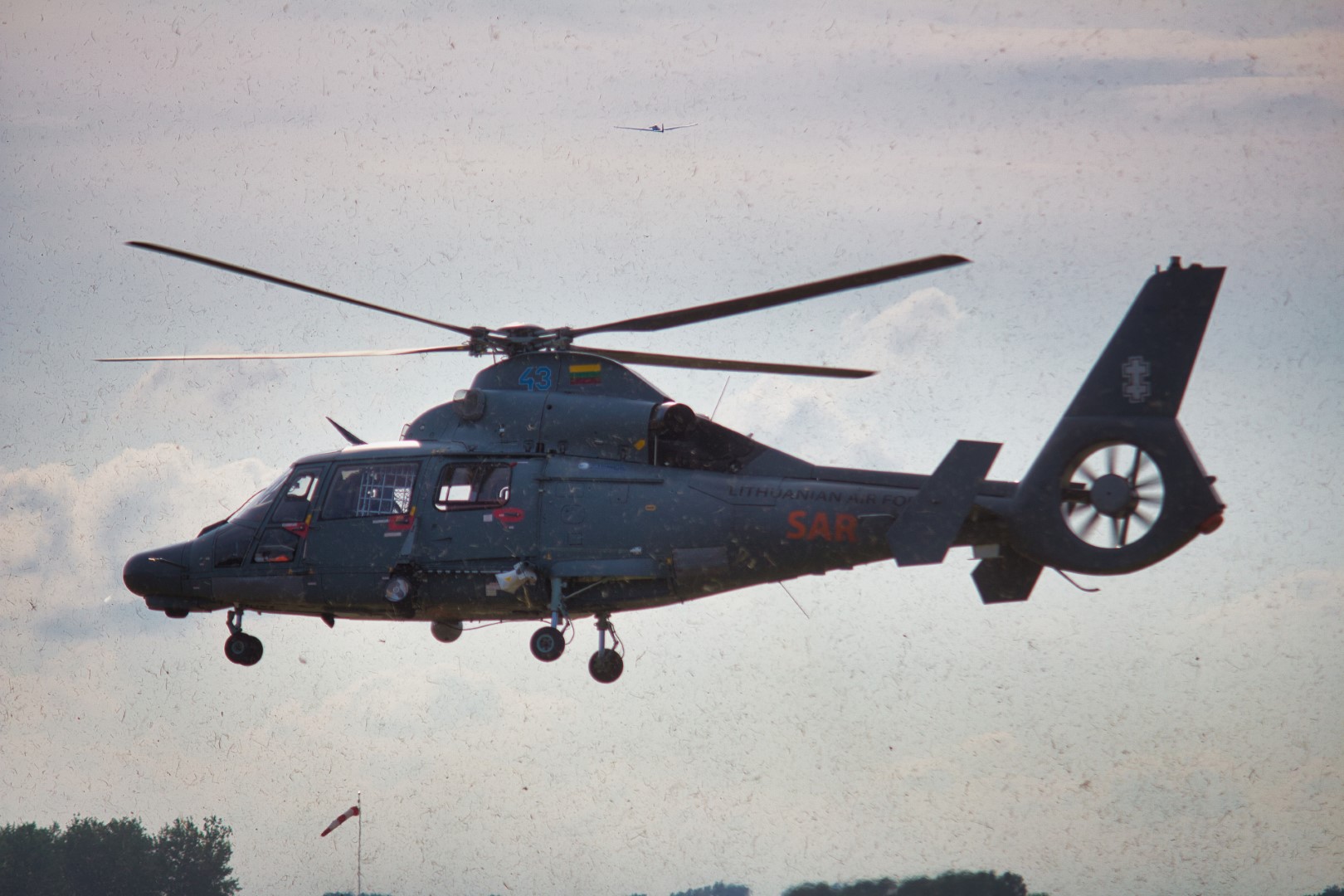 A photo of a helicopter kicking up grass and dirt as it takes off